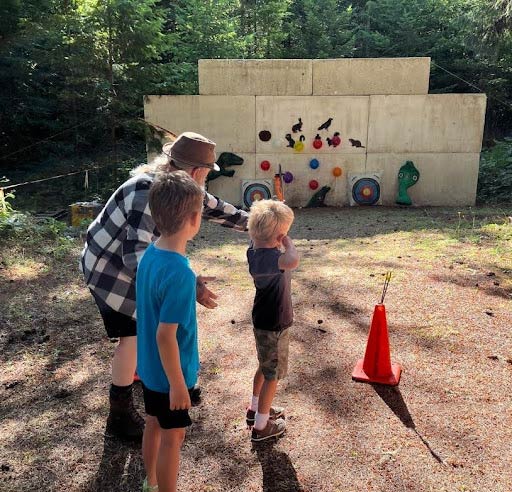 Two youngsters learning how to shoot a bow for the first time